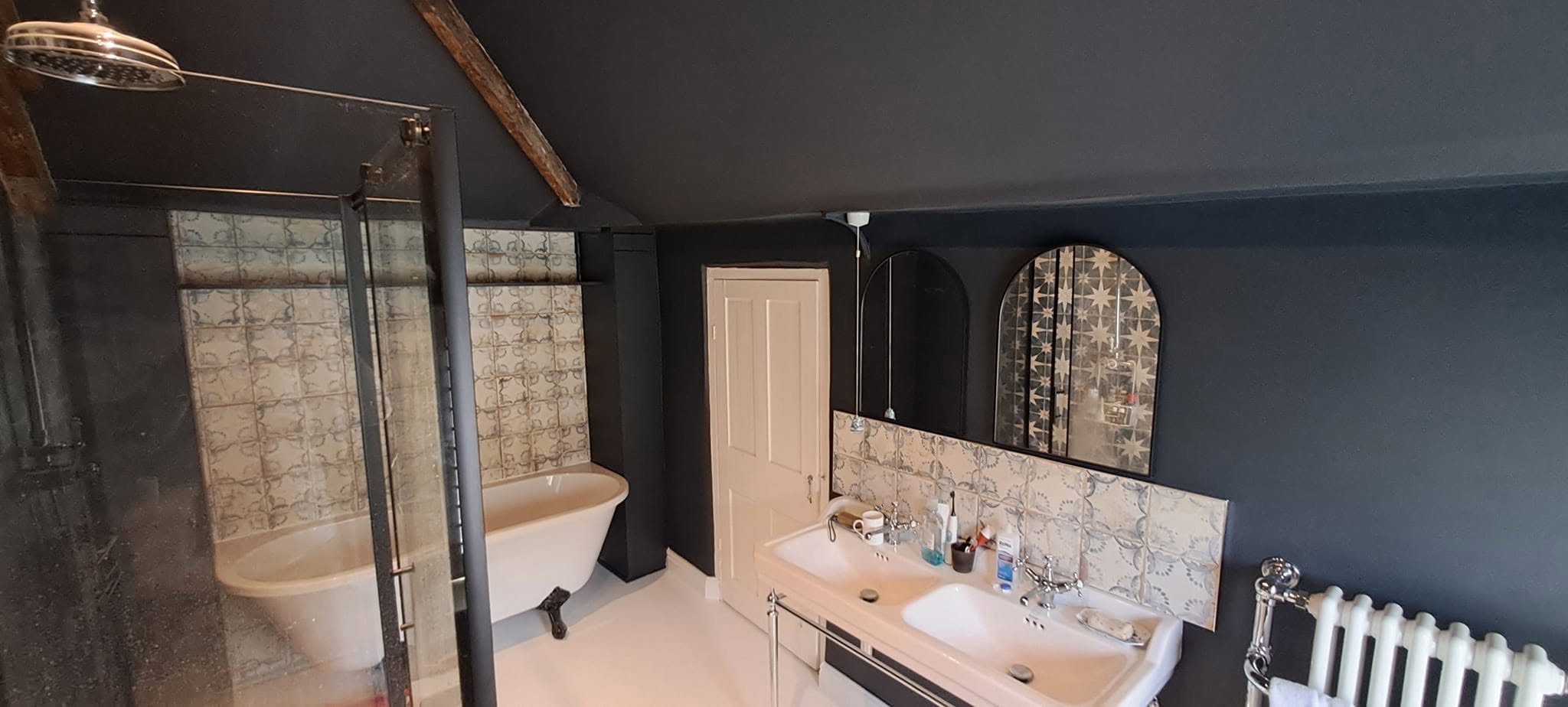 Finished bathroom with navy walls, roll-top bath, patterned tiles and a white painted floor