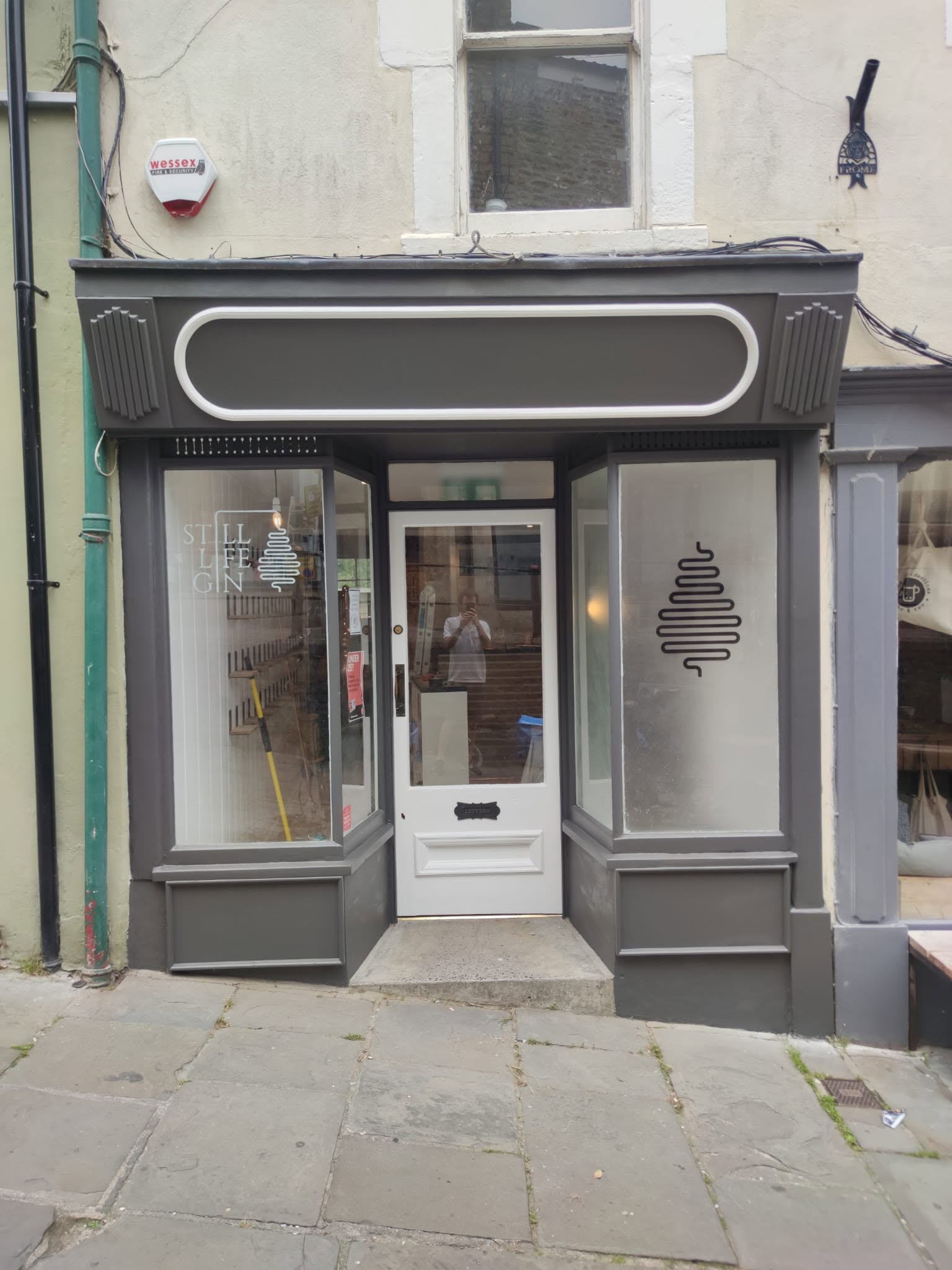 Shopfront repainted in dark grey with a cream front door