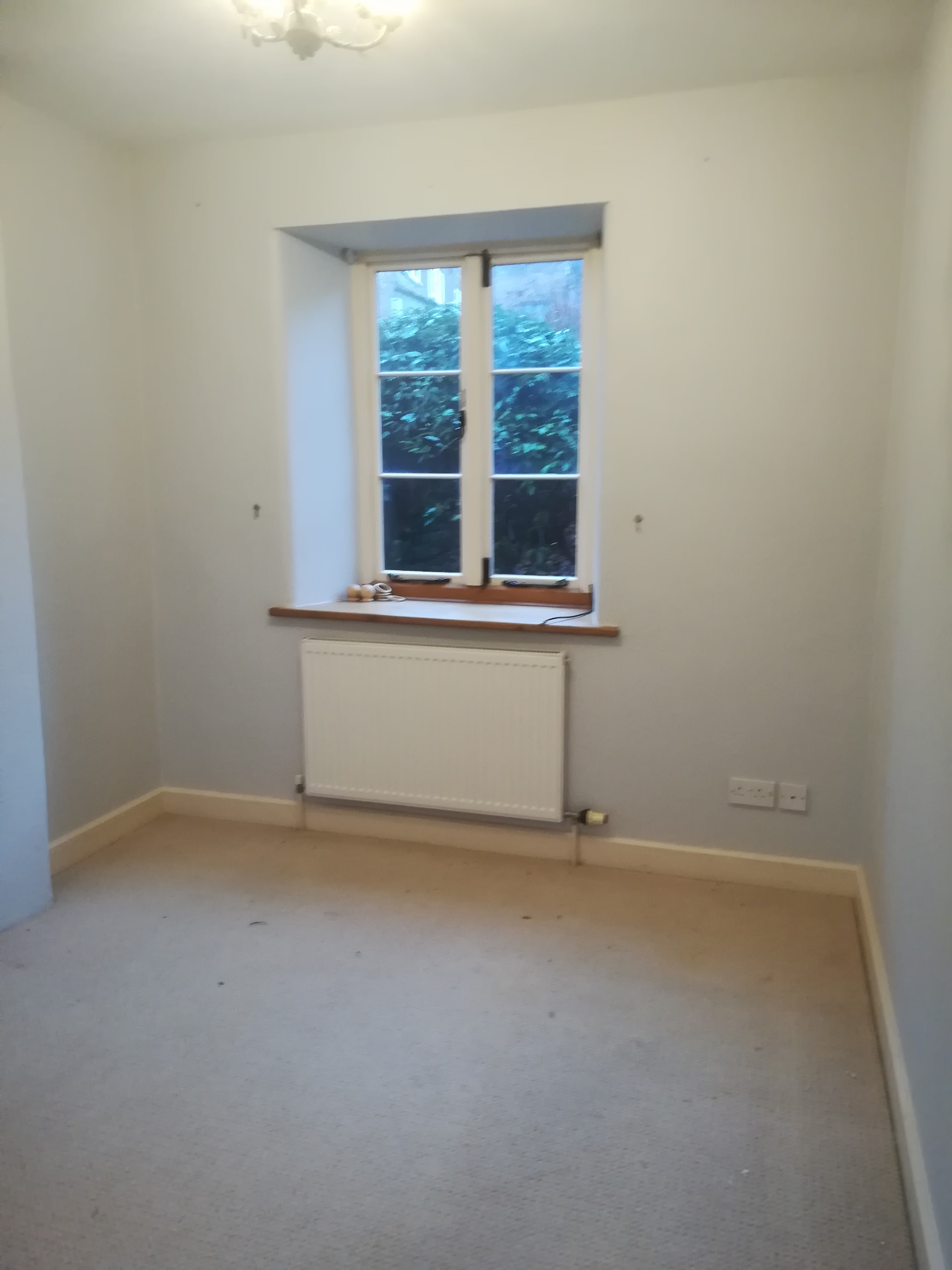 Freshly painted bedroom with pale walls, a white window and radiator