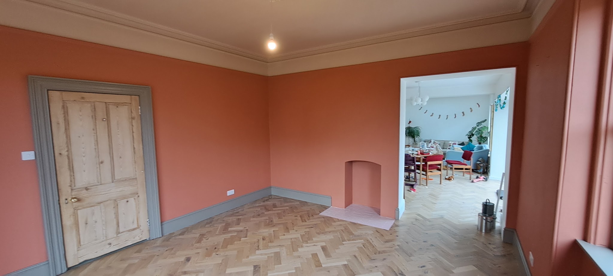 Finished room with terracotta walls, grey skirting and a stripped pine door