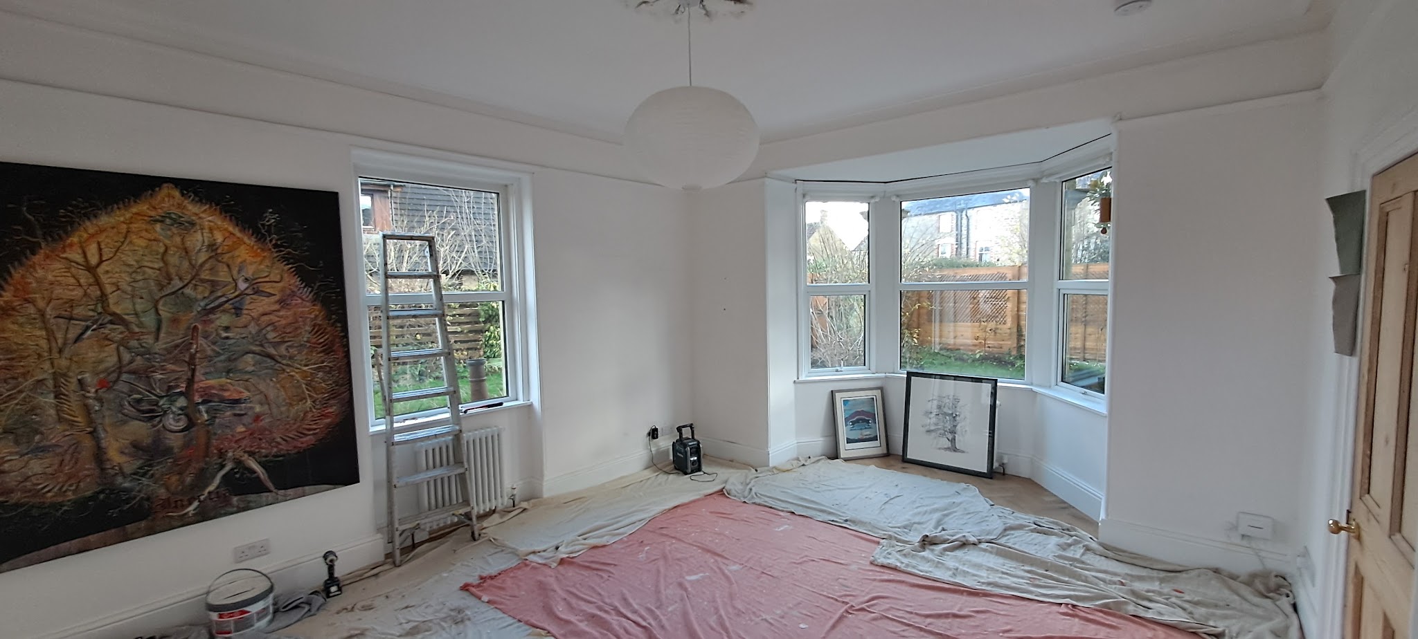 Bay window living room during painting, dust sheets down and a ladder by the window